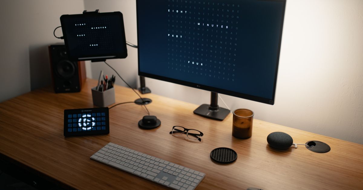 From above of flat screen computer and keyboard placed on wooden table with modern gadgets and monitors in workspace